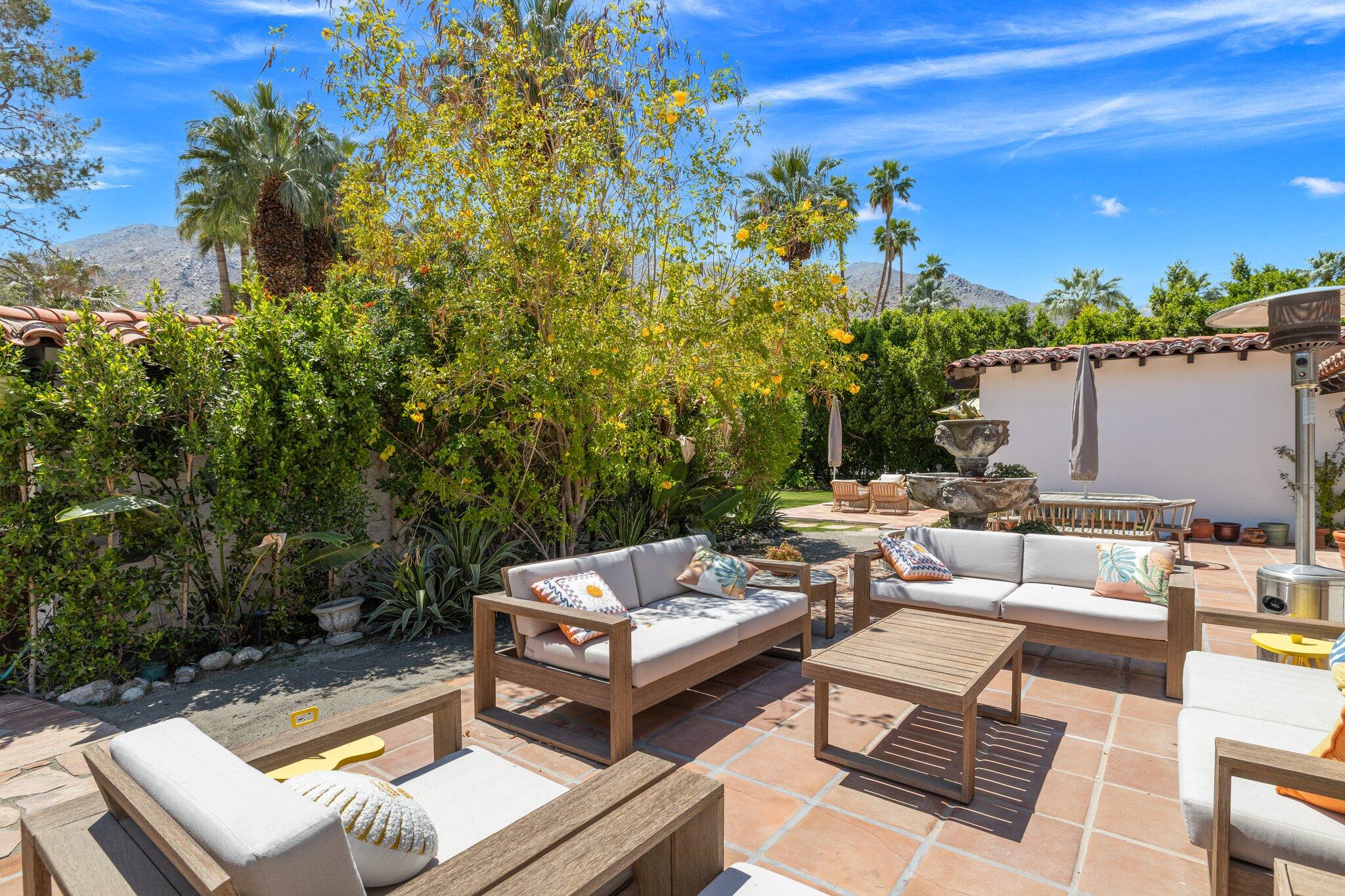 435 West Vereda Sur Palm Springs, CA 92262 - Photo 32 of 80 a view of a patio with couches and a table and chairs with wooden floor and fence