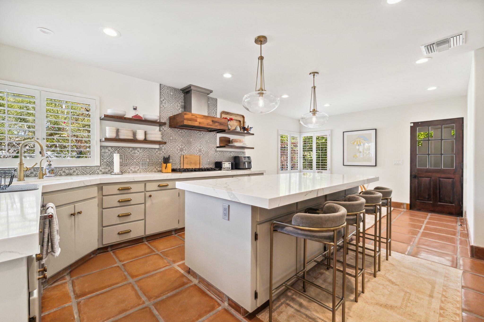 435 West Vereda Sur Palm Springs, CA 92262 - Photo 50 of 80 a kitchen with stainless steel appliances granite countertop a stove a sink a oven a dining table and chairs with wooden floor