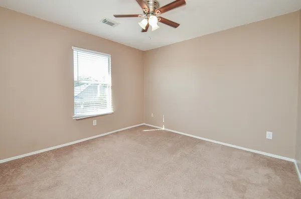 an empty room with a window and a fan