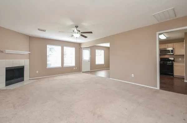 a view of an empty room with a ceiling fan and fireplace