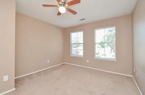 an empty room with windows and fan