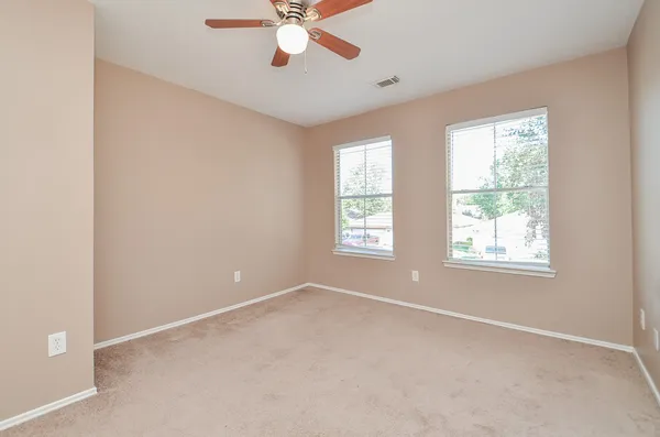 an empty room with windows and fan