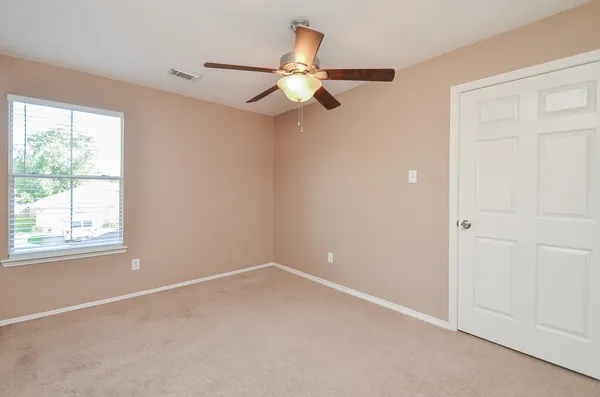 an empty room with a window and a fan