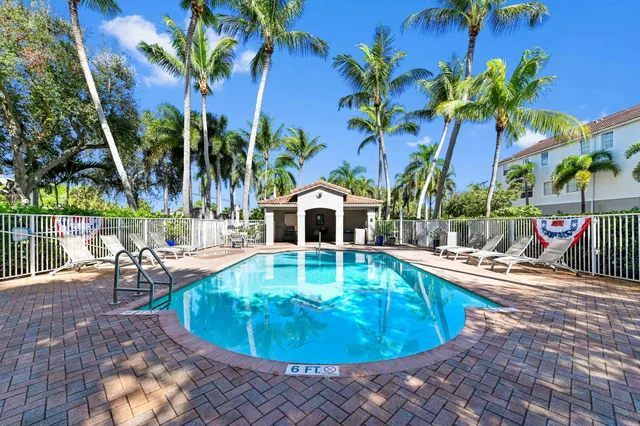 a view of a swimming pool with a lounge chair and palm trees