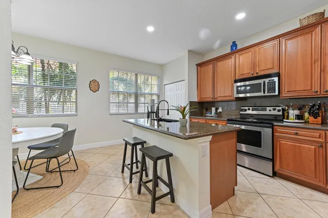 a kitchen with stainless steel appliances granite countertop a stove top oven a sink a dining table and chairs