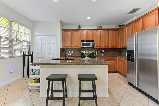 a kitchen with kitchen island granite countertop a table chairs microwave and refrigerator