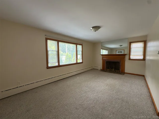 an empty room with windows & fireplace