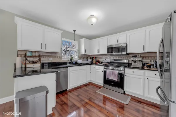 a kitchen with stainless steel appliances granite countertop a stove top oven a sink and white cabinets