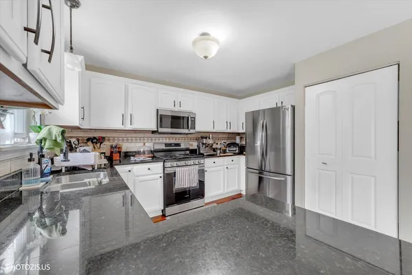 a kitchen with stainless steel appliances granite countertop a refrigerator a stove and a sink