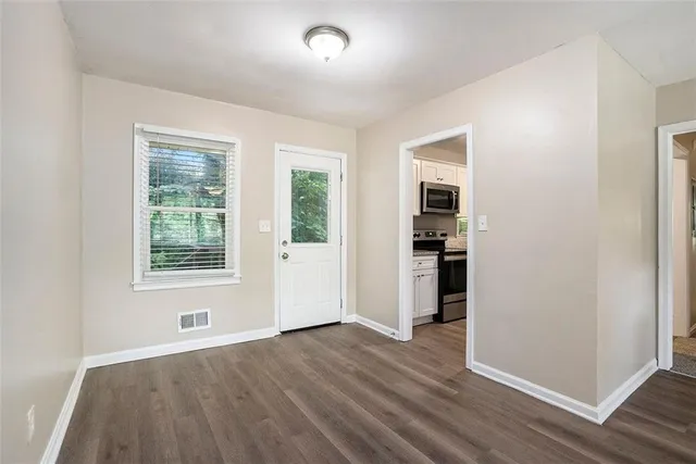 an empty room with wooden floor and windows