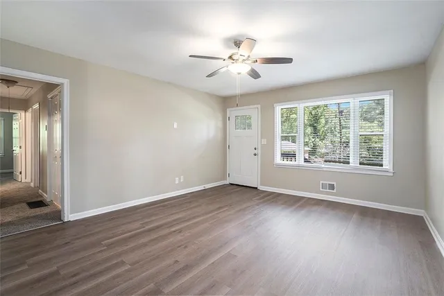 a view of an empty room with wooden floor and a window