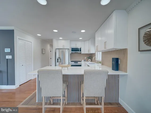 a kitchen with stainless steel appliances granite countertop a refrigerator a stove a sink a dining table and chairs