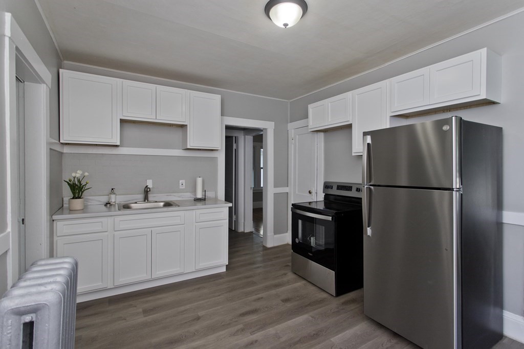 52-54 Draper Street Springfield, MA 01108 - Photo 17 of 31 a kitchen with a refrigerator stainless steel appliances wooden floor and cabinets