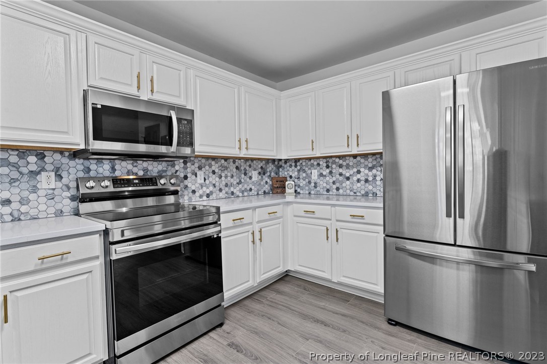3625 Marshlane Way Raleigh, NC 27610 - Photo 11 of 37 a kitchen with stainless steel appliances white cabinets granite counter tops and a stove top oven