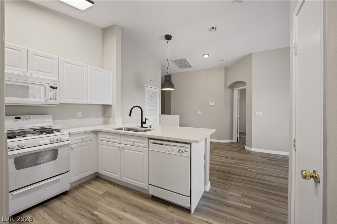 8777 Roping Rodeo Avenue, Unit 101 Las Vegas, NV 89178 - Photo 8 of 25 A well-lit kitchen with sleek white cabinetry and modern appliances, creating a fresh and inviting atmosphere.