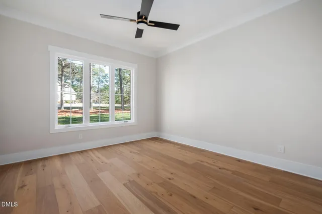 a view of an empty room with a window and kitchen view