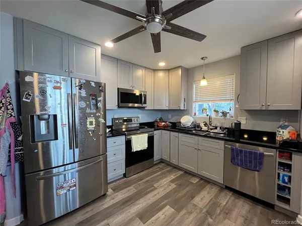 a kitchen with granite countertop a refrigerator a sink a stove a microwave and cabinets