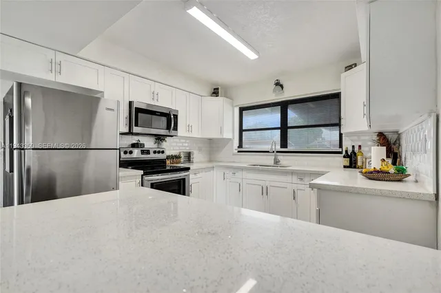 a kitchen with white cabinets and stainless steel appliances