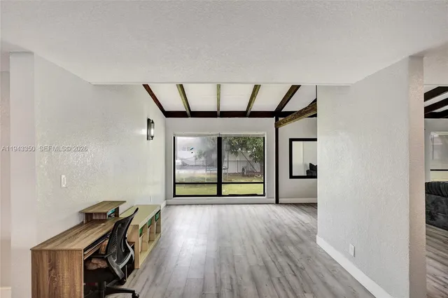 a view of a hallway with wooden floor and a livingroom