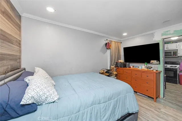 a bedroom with bed and flat tv screen on the dresser