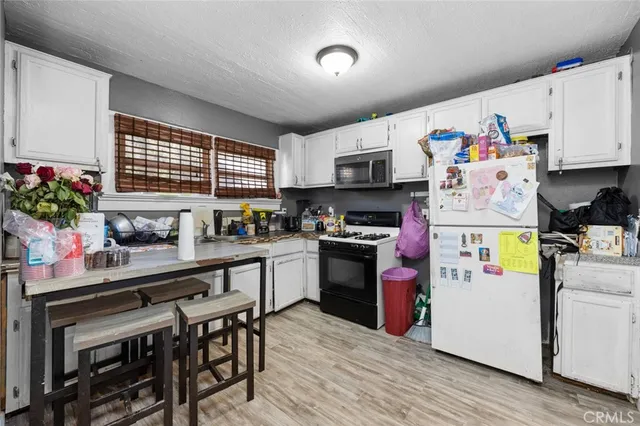 a kitchen with kitchen island a stove a sink dishwasher and white refrigerator with wooden floor