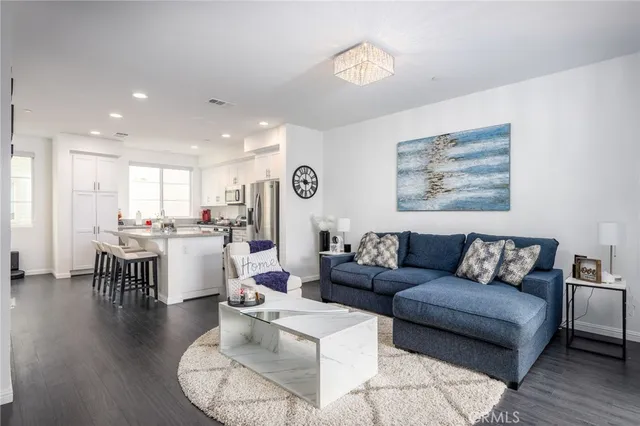 a kitchen with kitchen island granite countertop a stove top oven a sink dishwasher and a refrigerator with wooden floor