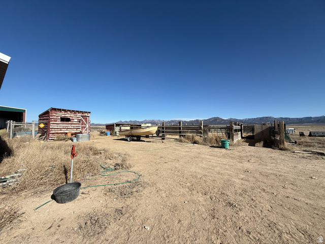 3550 North River Ln Road East Panguitch, UT 84759 - Photo 4 of 25 Expansive outdoor area featuring a rustic red-painted storage shed, a large green metal building, and extensive wooden fencing