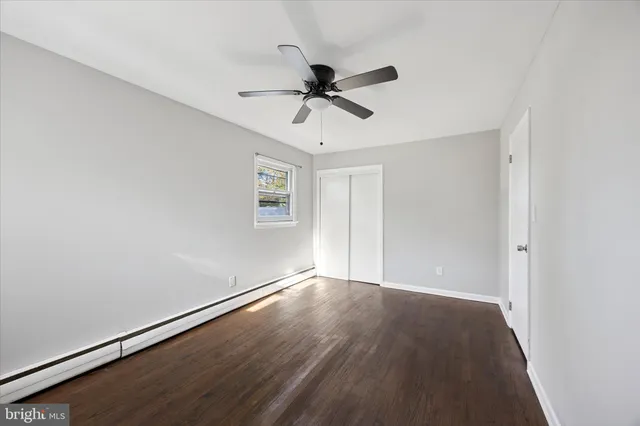 an empty room with wooden floor fan and windows
