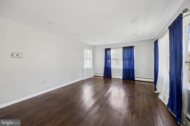 a view of an empty room with wooden floor and window