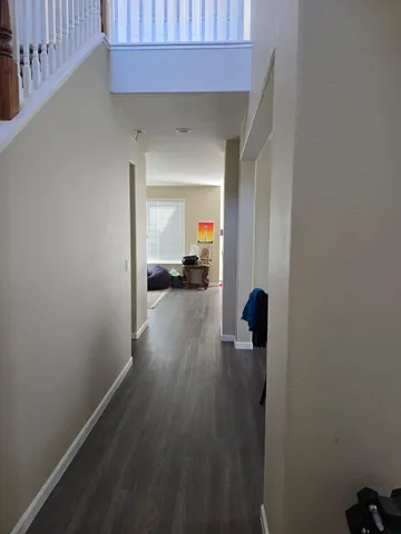 a view of a hallway with wooden floor and a living room