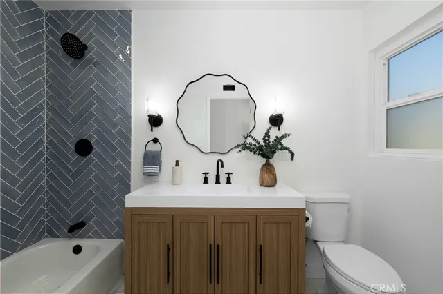 a bathroom with a sink and mirror with bathtub