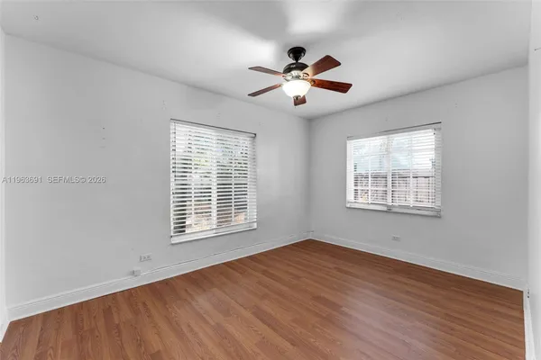 a view of an empty room with wooden floor and a window