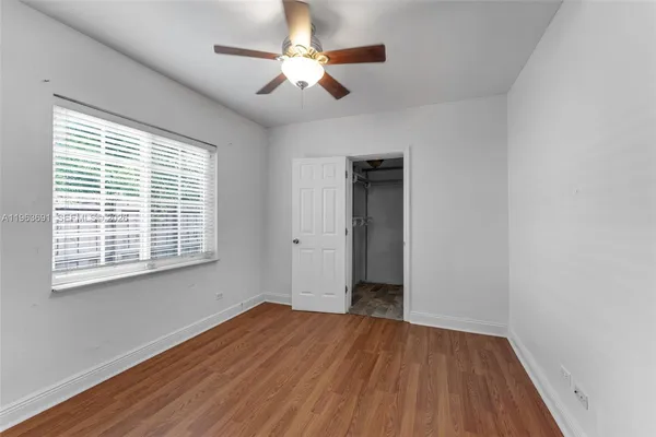 a view of empty room with wooden floor and fan