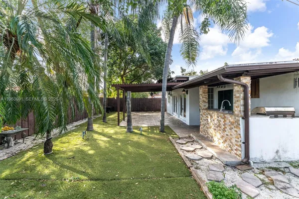 a view of a backyard with wooden fence and a large tree