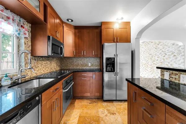 a kitchen with stainless steel appliances granite countertop a sink a stove and a refrigerator