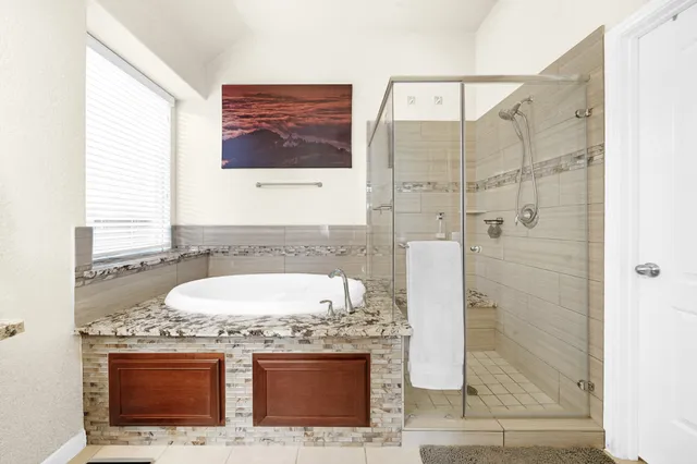 a bathroom with a granite countertop sink a mirror and shower