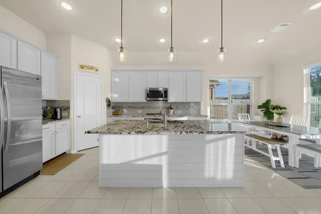 a kitchen with stainless steel appliances kitchen island granite countertop a stove a sink and a refrigerator