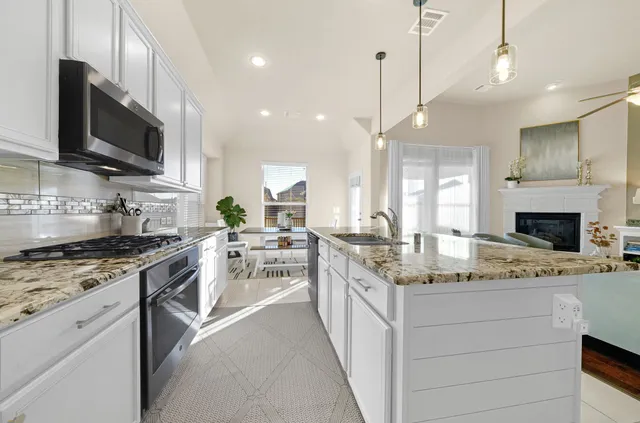 a kitchen with stainless steel appliances granite countertop a stove top oven a sink dishwasher a dining table and chairs with wooden floor