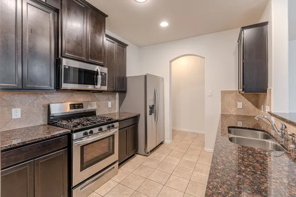 a kitchen with granite countertop a refrigerator stove and microwave