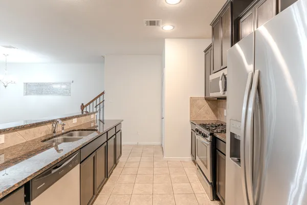 a kitchen with stainless steel appliances granite countertop a refrigerator and a sink