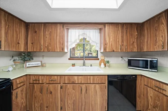 a kitchen with stainless steel appliances a sink a stove a microwave cabinets and a counter top space