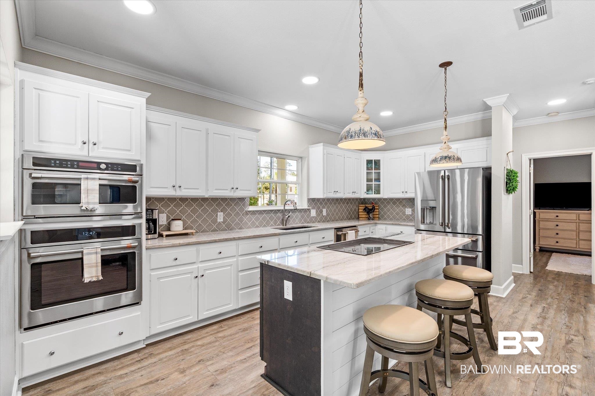 4947 Look Rook Road Orange Beach, AL 36561 - Photo 5 of 24 Kitchen with visible vents, a sink, a kitchen bar, white cabinetry, and stainless steel appliances