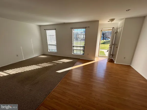 a view of an empty room with window and wooden floor