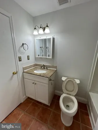 a bathroom with a granite countertop toilet a sink and a mirror