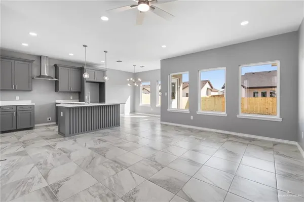 a view of an empty room with kitchen and window