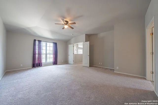 a view of empty room with windows and ceiling fan