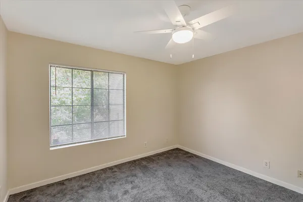 an empty room with a window and a fan
