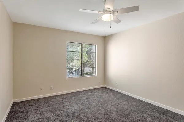 an empty room with closet and a ceiling fan