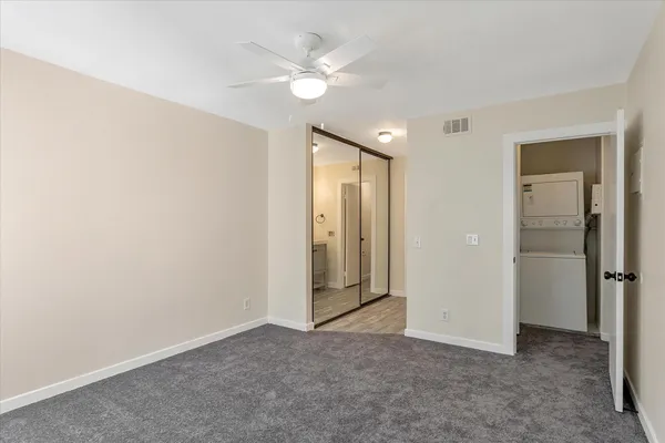 an empty room with closet and a ceiling fan