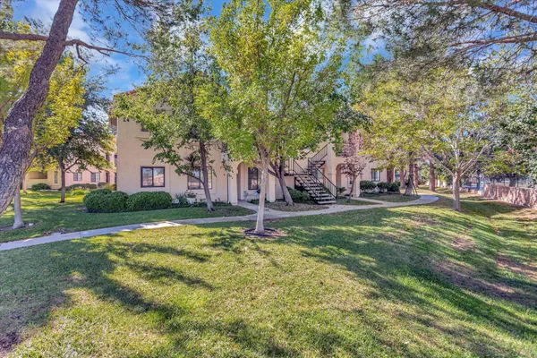 a front view of a house with a yard and large trees